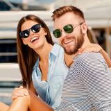 Smiling couple wearing sunglasses by the water at a marina
